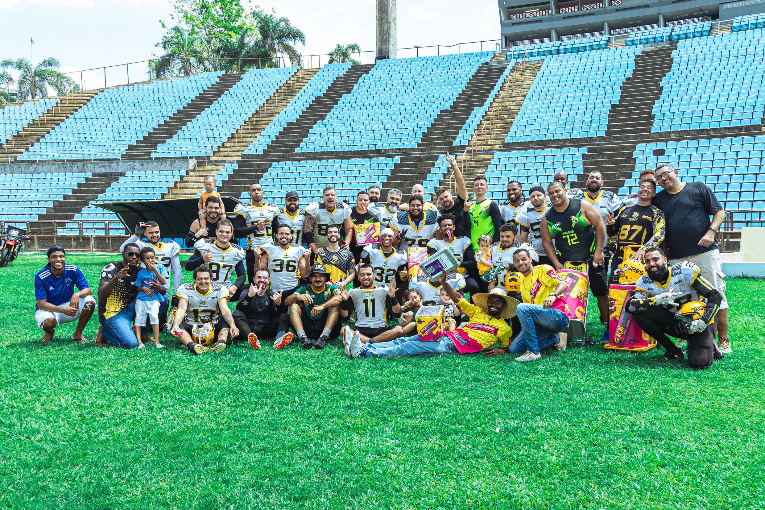 Elenco do Tigres FA reunido no gramado do estádio, comemorando com troféus e torcedores