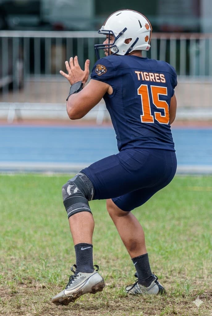 Quarterback do Tigres FA, camisa 15, em posição de passe durante o treino